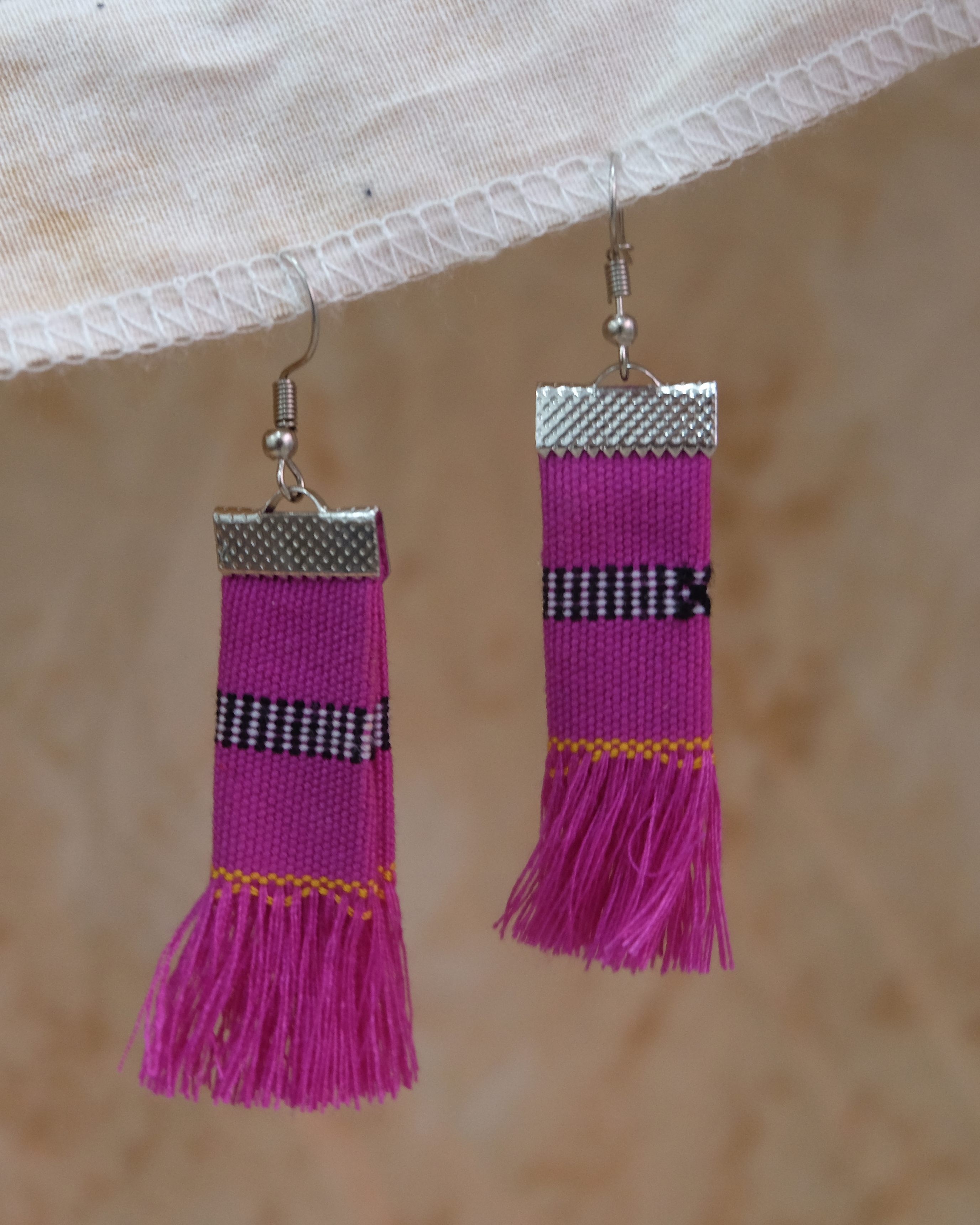 Handwoven Kalinga tassel earrings in fuchsia pink with black and yellow striped patterns, made from traditional Filipino woven fabric with fringe ends