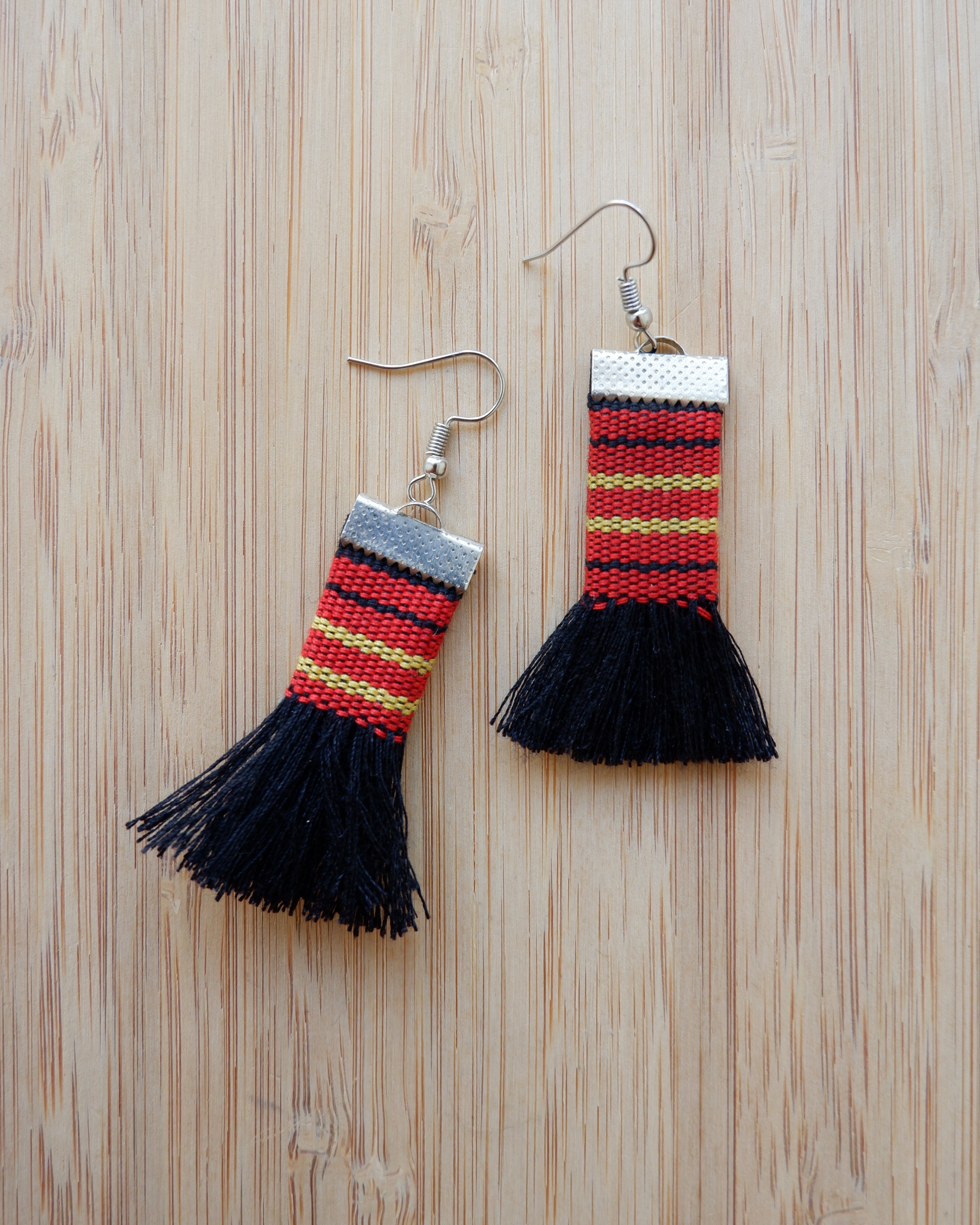 Black Kalinga tassel earrings made from handwoven red, yellow, and black fabric, Filipino artisan jewelry.