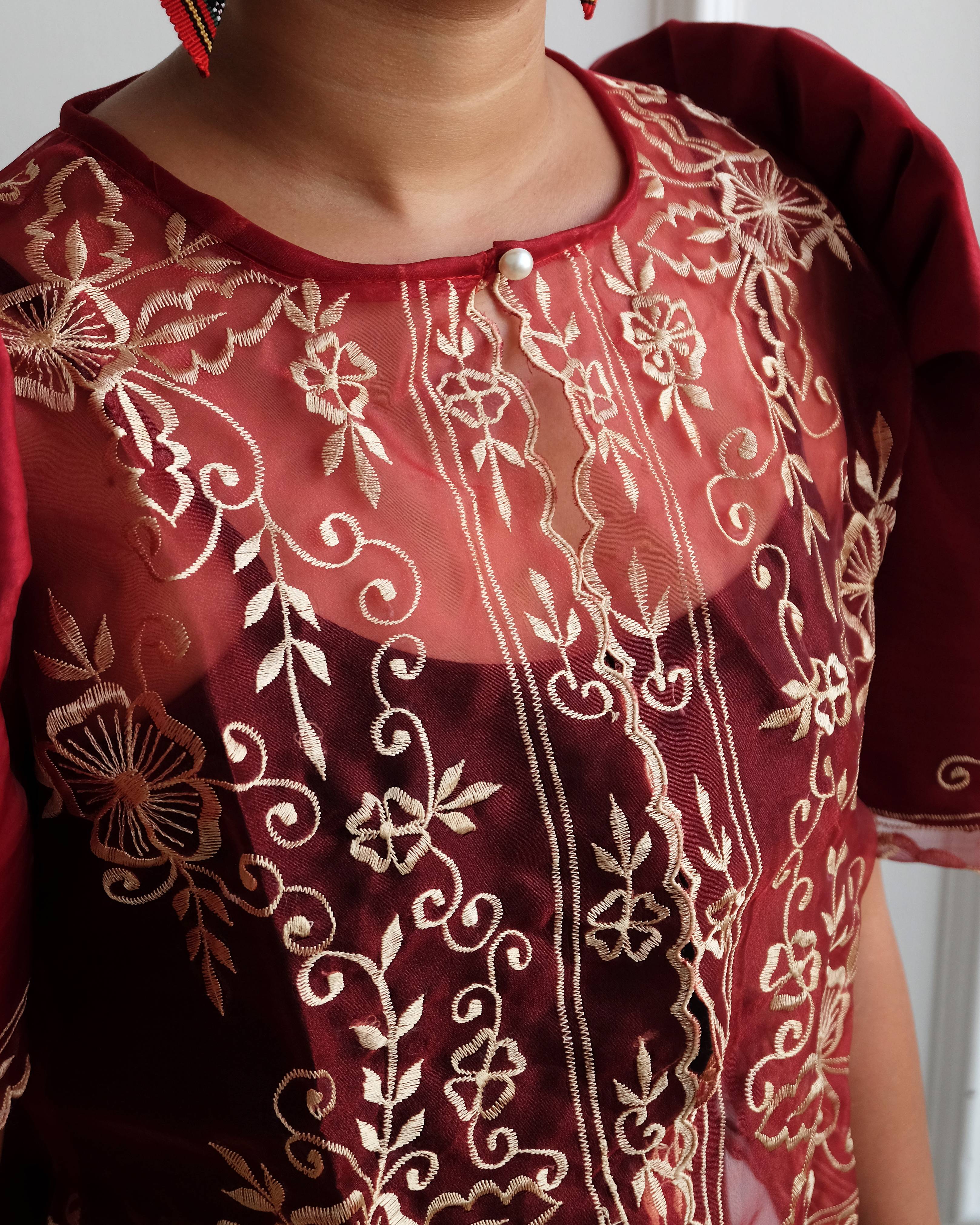 A maroon Filipiniana bolero blouse with floral embroidery on sheer organza fabric, featuring iconic butterfly sleeves.