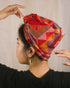 A vibrant, handwoven Yakan headscarf with geometric patterns in red, orange, yellow, purple, and pink hues. Yakan Headscarf Unisex Headscarf | Narra Studio
