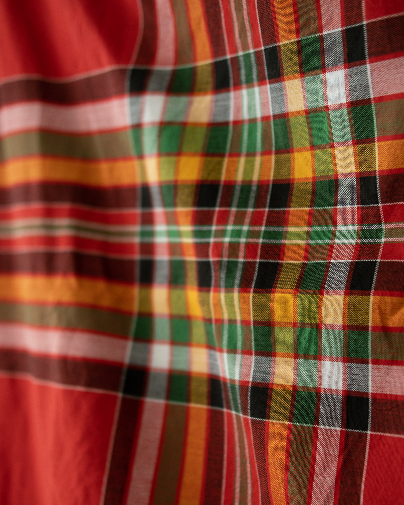 A handwoven Tboli malong in standard length, featuring traditional plaid patterns in bold red, green, yellow, black, and white. The fabric showcases vibrant, intersecting stripes and fine craftsmanship.