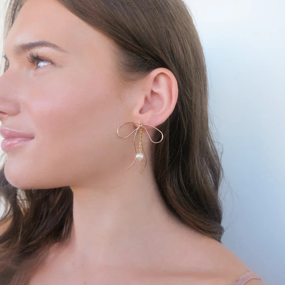 Lazo Threader Earrings with gold bow-shaped wire design and dangling pearl charm, handcrafted by Filipino artisans