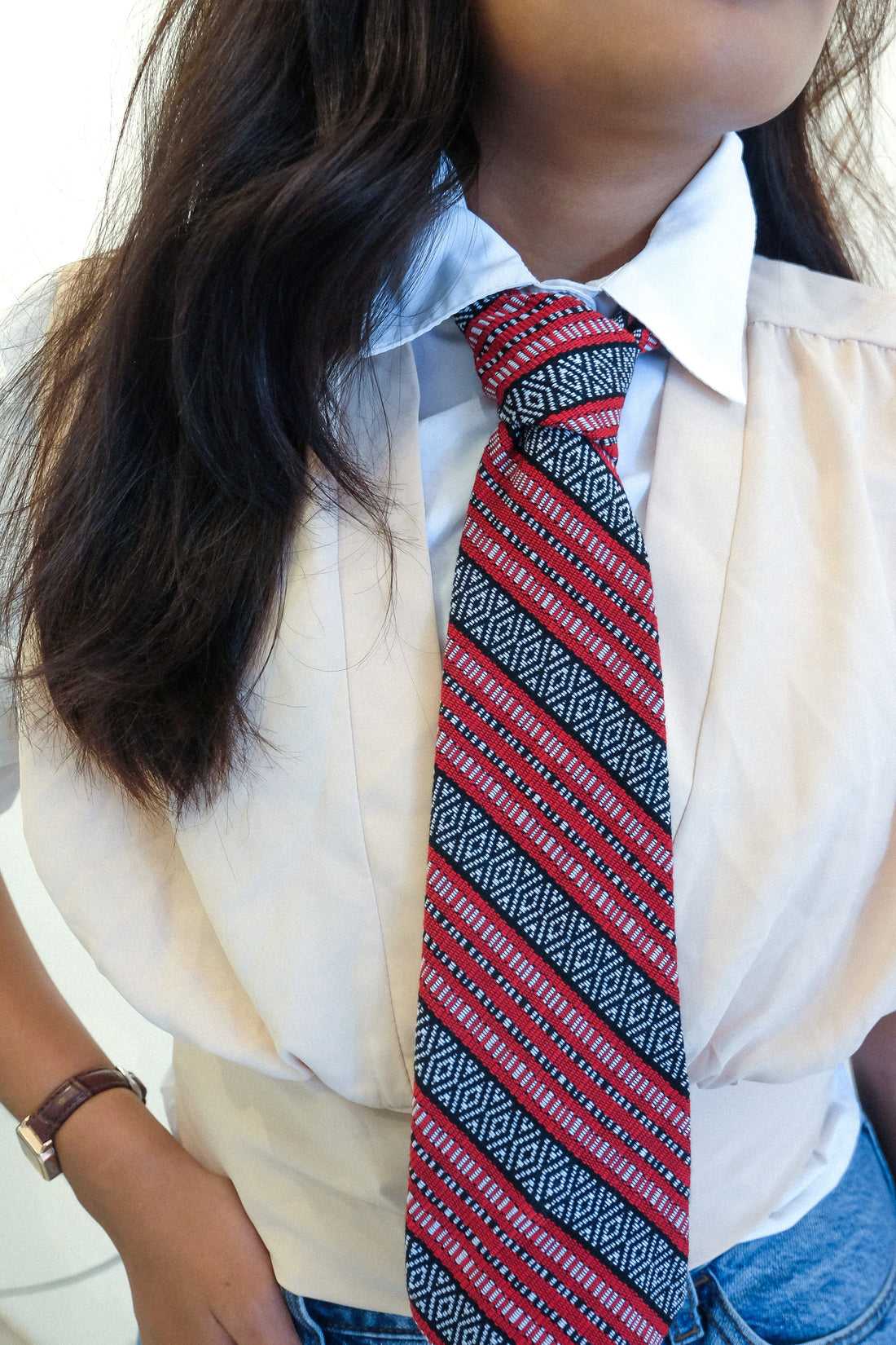 Handwoven Isabela Necktie in Red striped polycotton necktie featuring traditional diamond and stripe patterns from Isabela, Philippines. Worn with a collared white blouse, styled in a modern, semi-formal look.