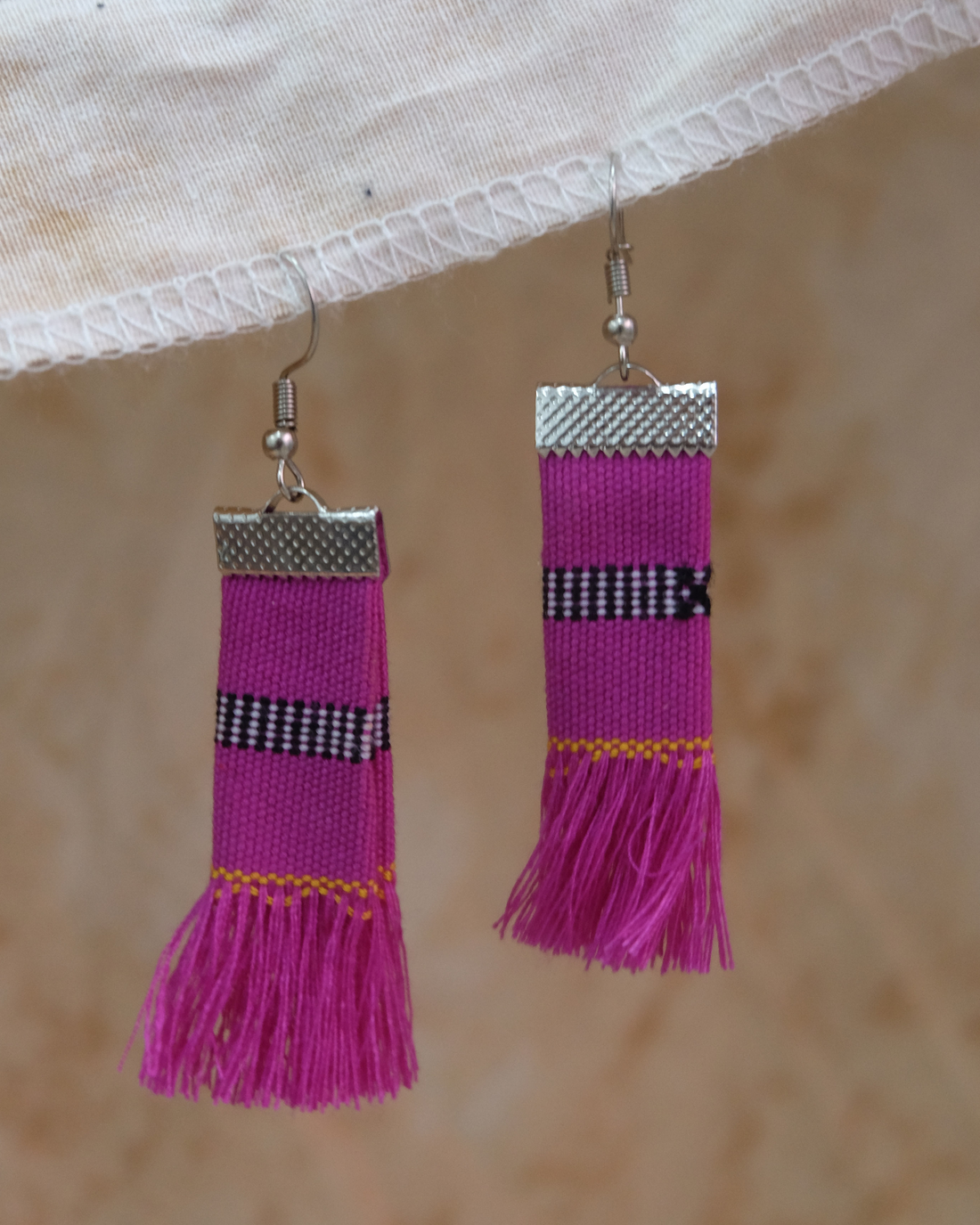 Handwoven Kalinga tassel earrings in fuchsia pink with black and yellow striped patterns, made from traditional Filipino woven fabric with fringe ends