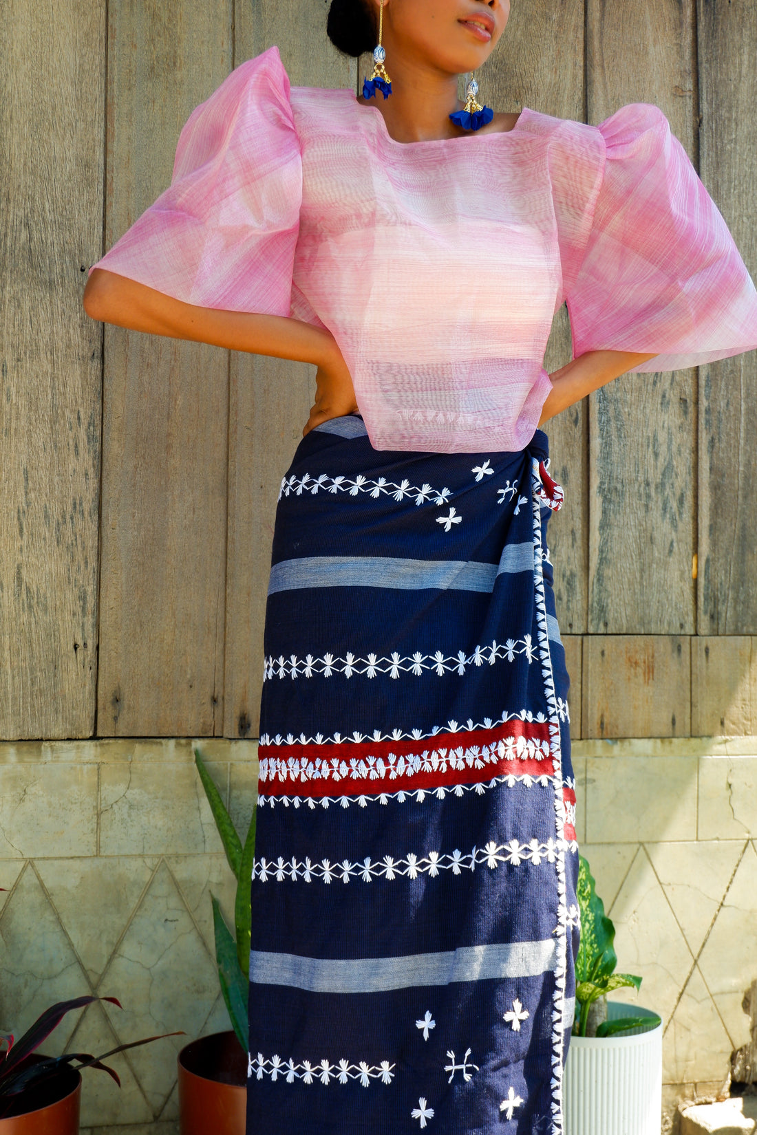 A traditional Filipino outfit featuring a handwoven navy tapis wrap skirt with intricate white and red embroidery in geometric patterns. 