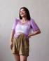 A woman in a modern Ube (purple) sheer Filipiniana bolero, styled with a white tube top and casual shorts.