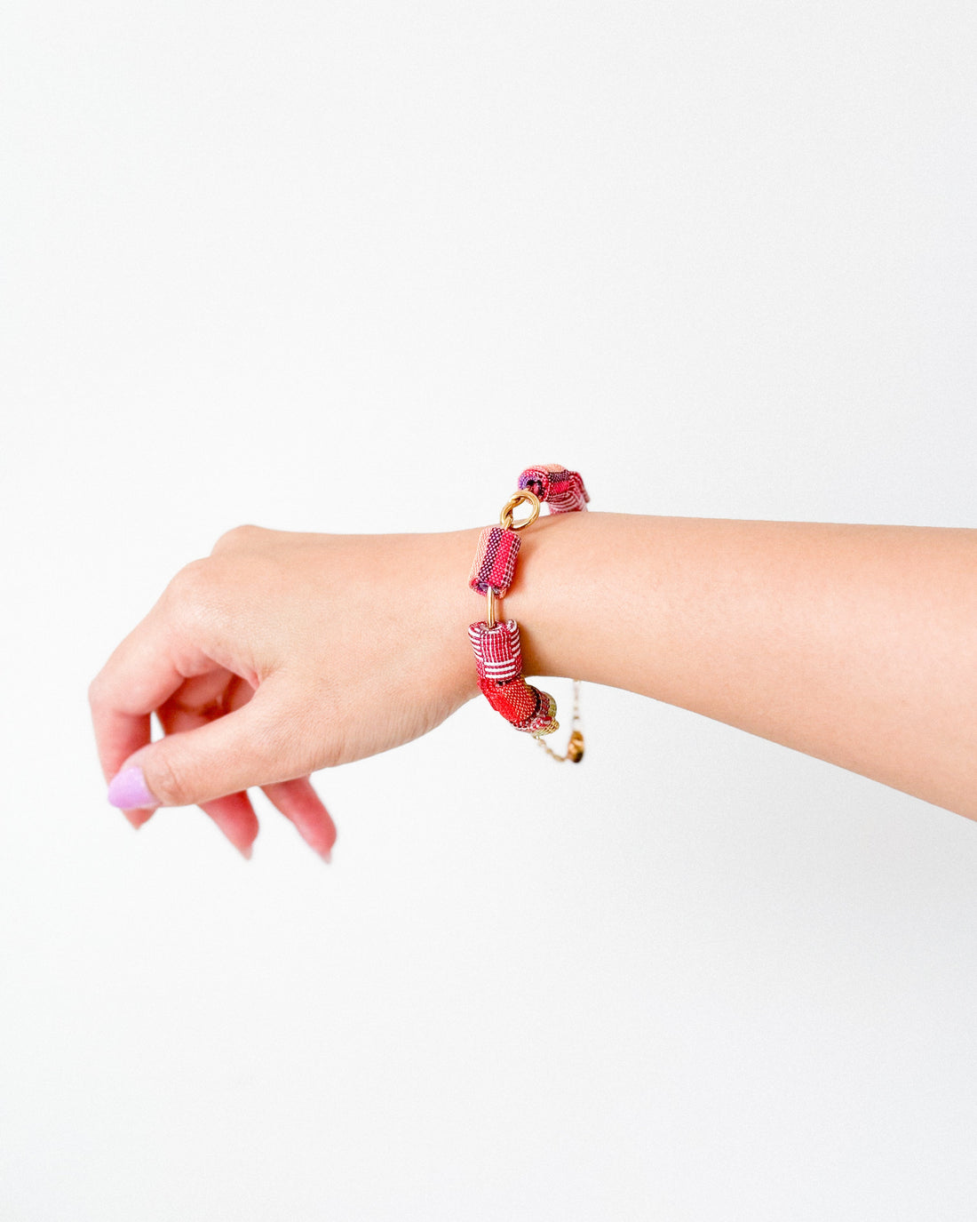 A pink Handwoven Lahi Knot Bracelet made from upcycled fabric. The zero-waste bracelet features intricate knots and Piesa wire.