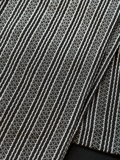 Handwoven sablay sash featuring horizontal patterns in black and white. The intricate geometric designs include X and diamond motifs, arranged in alternating bands that reflect traditional Filipino textile artistry.