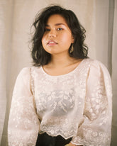 A traditional Filipino Camisa blouse in natural white silk organza, featuring hand-embroidered floral details, a cropped fit, and a scalloped hem.